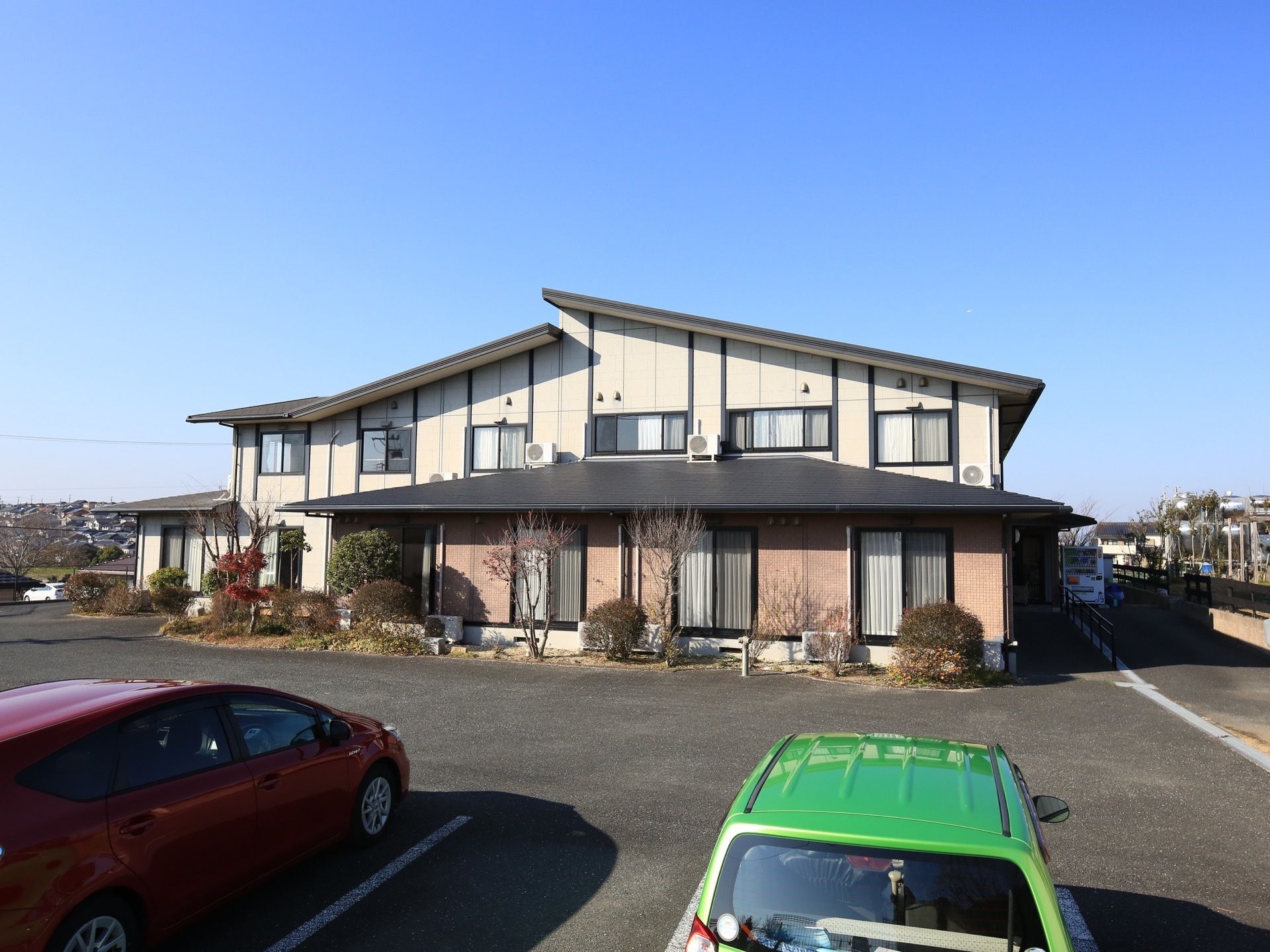 住宅地と草地の中程にある、静かな立地の建物である。駐車場と隣接しており、玄関付近には手すりがある。