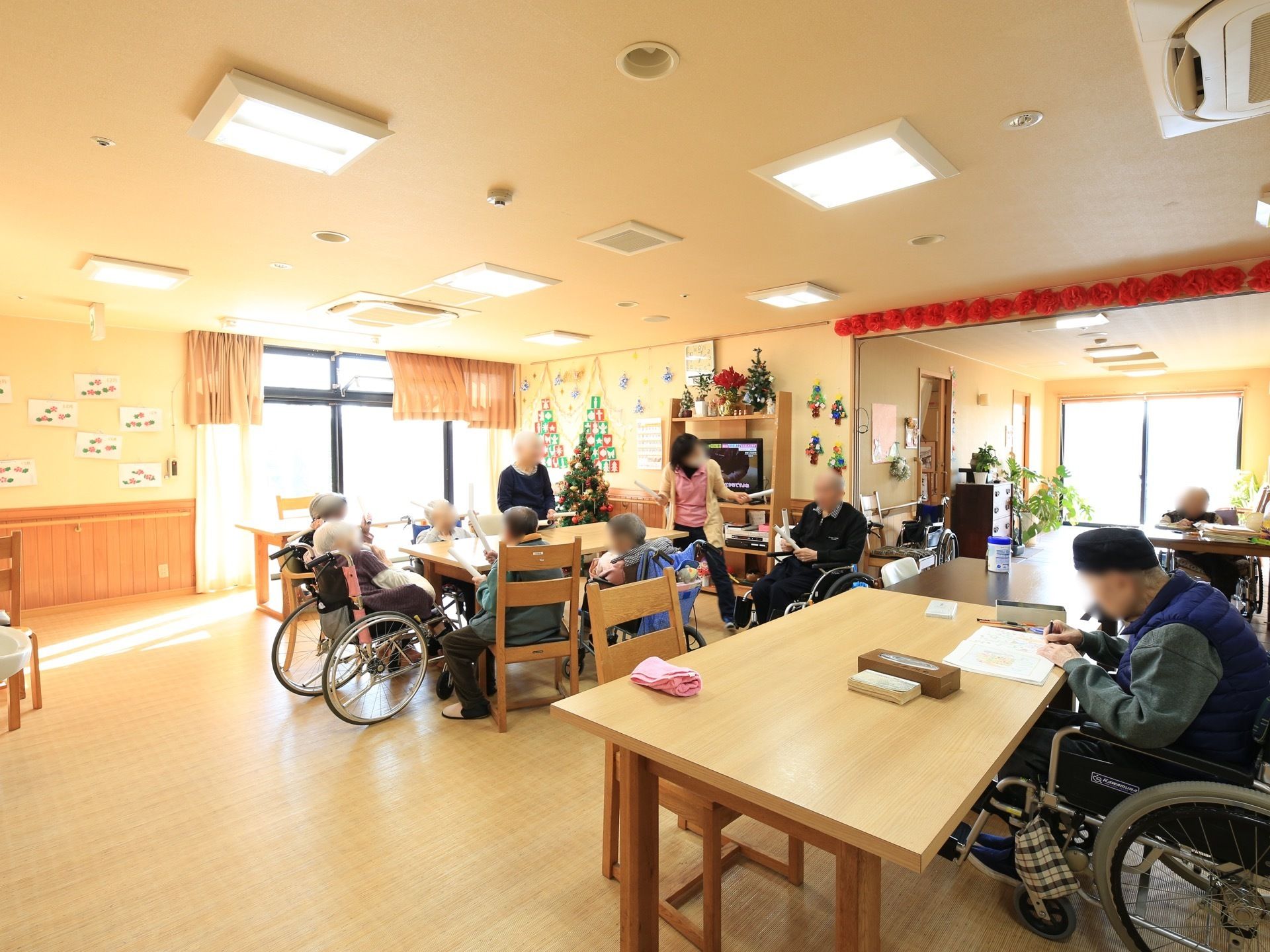 ２か所に大きな窓があり、屋外の光が感じられる共有スペースである。入居者様の作品や手作りの飾りが多く展示されている。