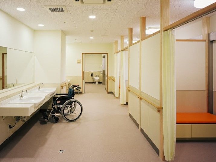 左側に洗面台と車いす、右側に仕切りのあるスペースがある場所
