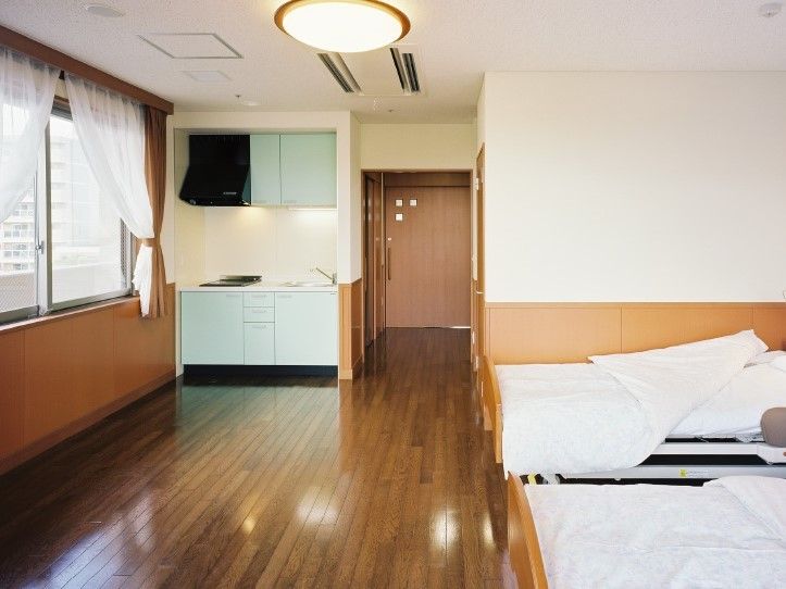 右側に２つのベッド、奥のほうにキッチンがある二人用の部屋の写真