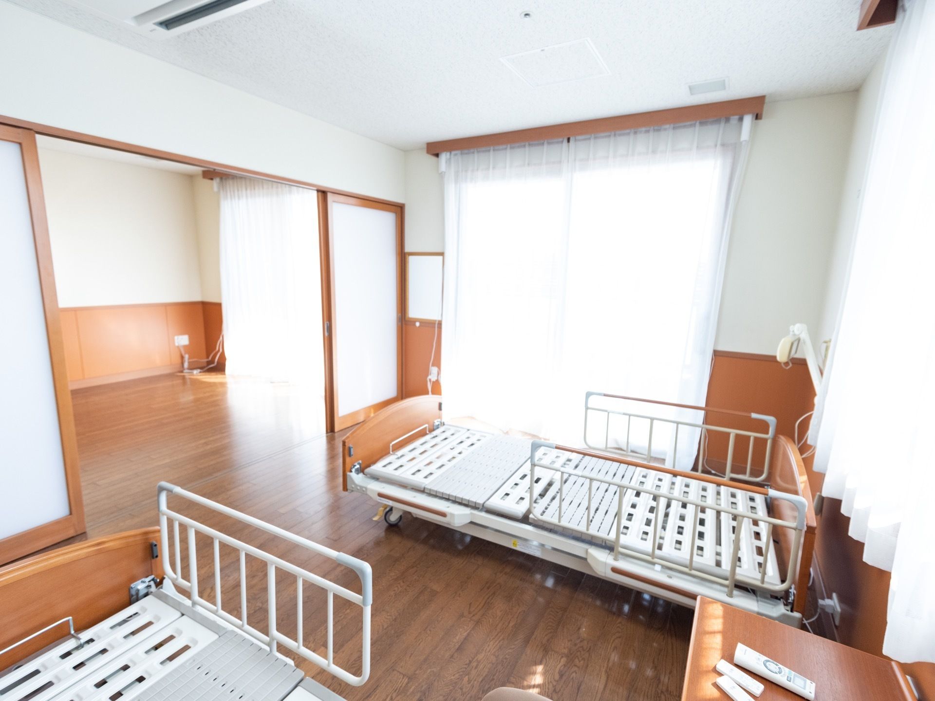 ２間続きの広い部屋があり、手前の部屋には介護用のベッドが２つ置かれている。周囲の壁には３つの窓があり、明るい自然の光が差し込んでいる。