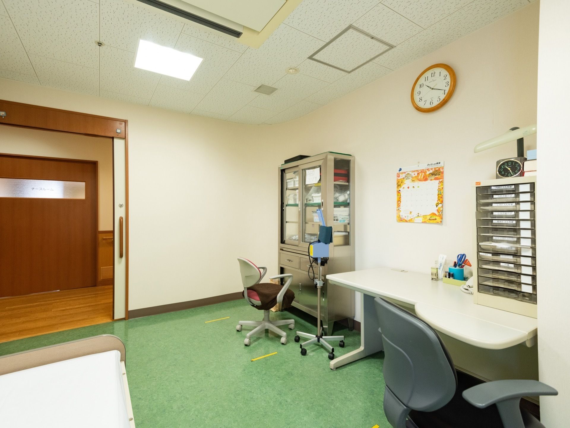 デスクと書類ケース、棚、ベッドなどが置かれている。壁には掛け時計が設置されている。入口の扉は大きめの引き戸である。