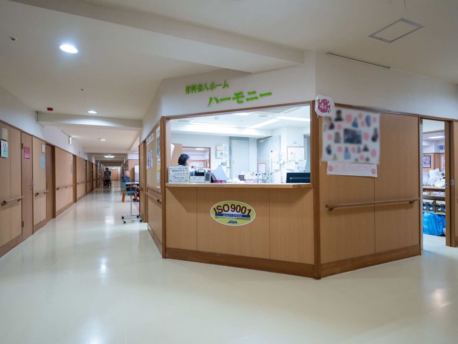 廊下の一角にあるスタッフルームである。廊下は幅があり、手すりも設置されている。スタッフルームの壁には施設名が書かれている。