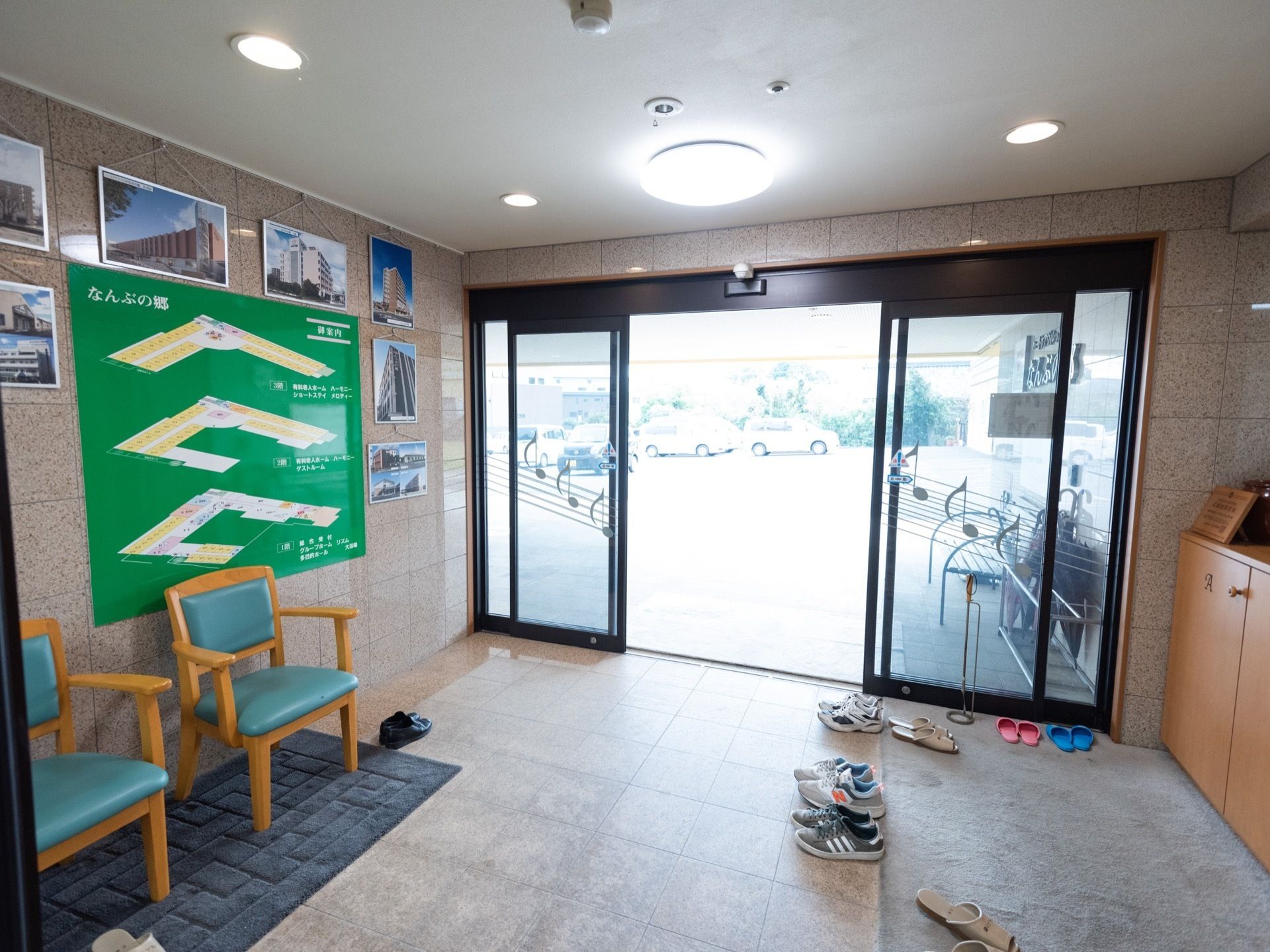 広さのある玄関である。大理石調の床と壁に黒枠のオートドアが設置されている。ガラスには、音符が描かれている。