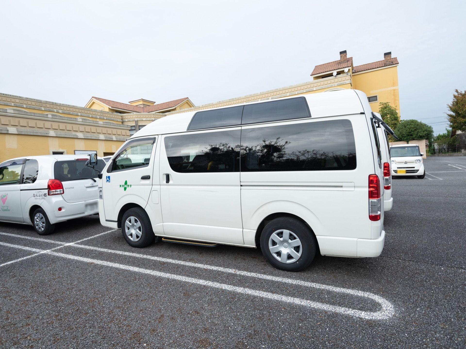 白い大型のワンボックスカーである。後部座席の窓は黒のスモークを貼っている。ボディには、施設名が記され障がい者マークが貼られている。
