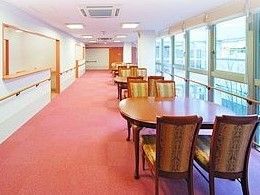 長い廊下にじゅうたんが敷いてある様子。窓側にリラックススペースとしてテーブルと椅子が置いてある