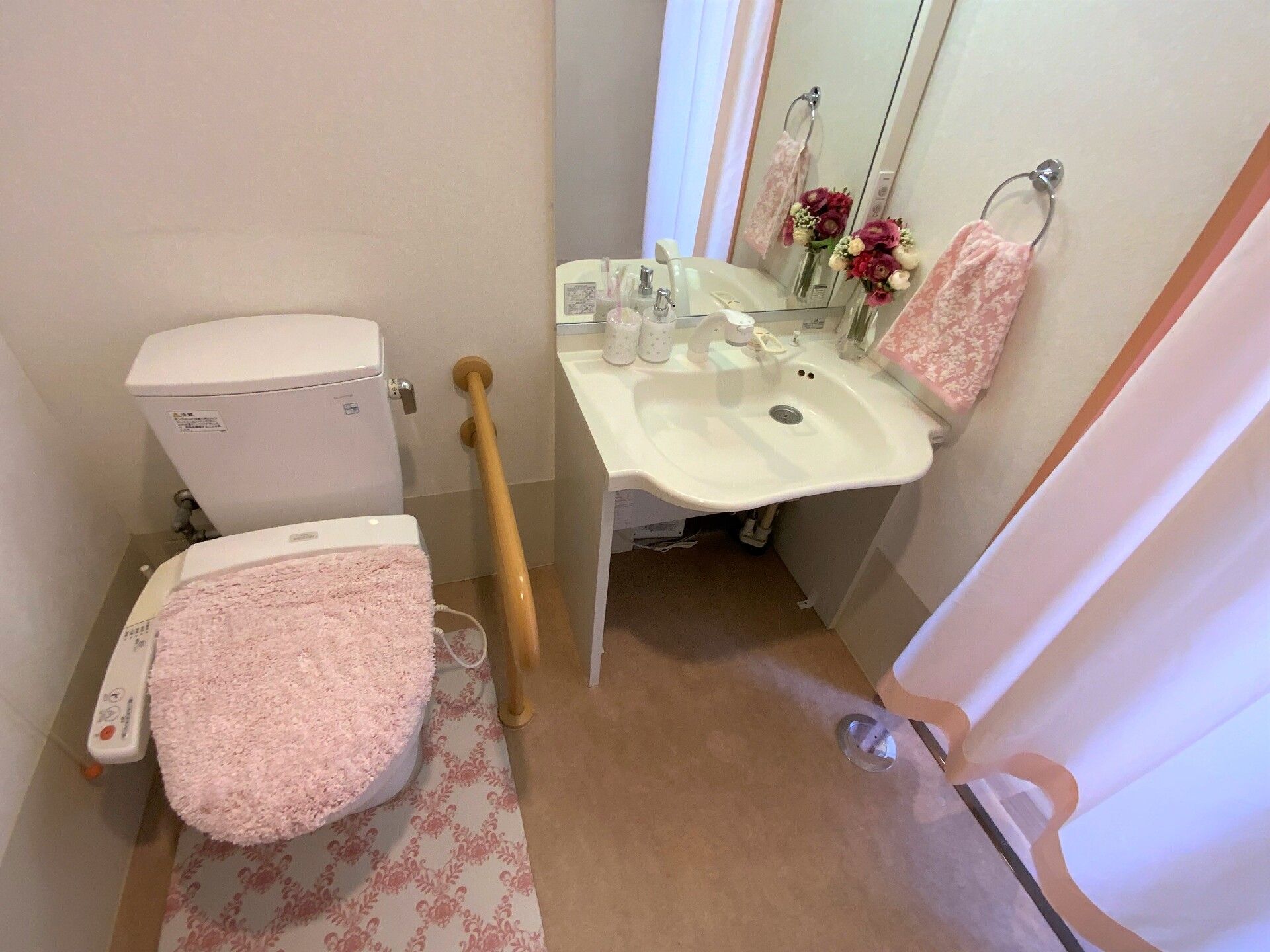 フットレスの洗面台付きトイレの様子。便器の両側に手すりが付いている様子