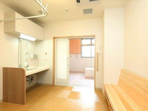 脱衣所と浴室の間に段差はなく、浴室には個浴、脱衣所には洗面台と木製のベンチがある。
