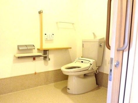 呼び出しボタンがついたトイレにはアイ字型の手すりがあり、便座にふたはなく、介助スペースも広い。