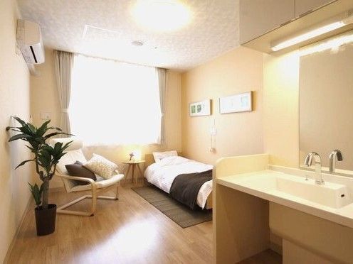 大きな窓があり明るい雰囲気。居室には、ベッドや収納家具、洗面所だけでなくエアコンもついている。