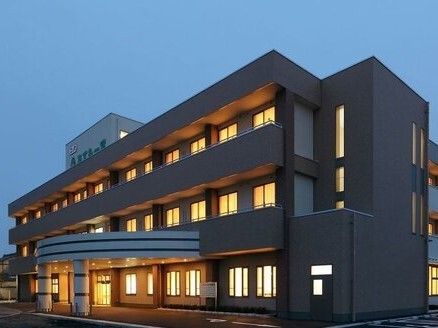 辺りが薄暗くなってきた夕暮れ。3階建ての建物の館内には明かりが灯り、玄関あたりもライトアップされている。