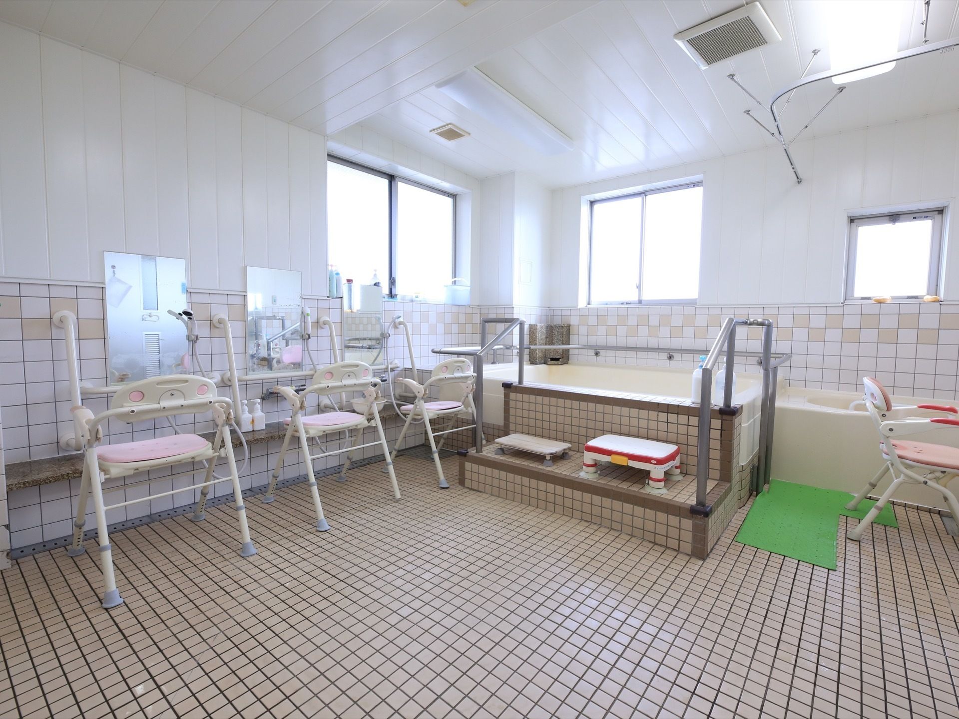 明るく開放的な浴室は、複数人が利用できるように洗い場が多数設置してある。安全のため、浴槽の階段に踏み台がある。