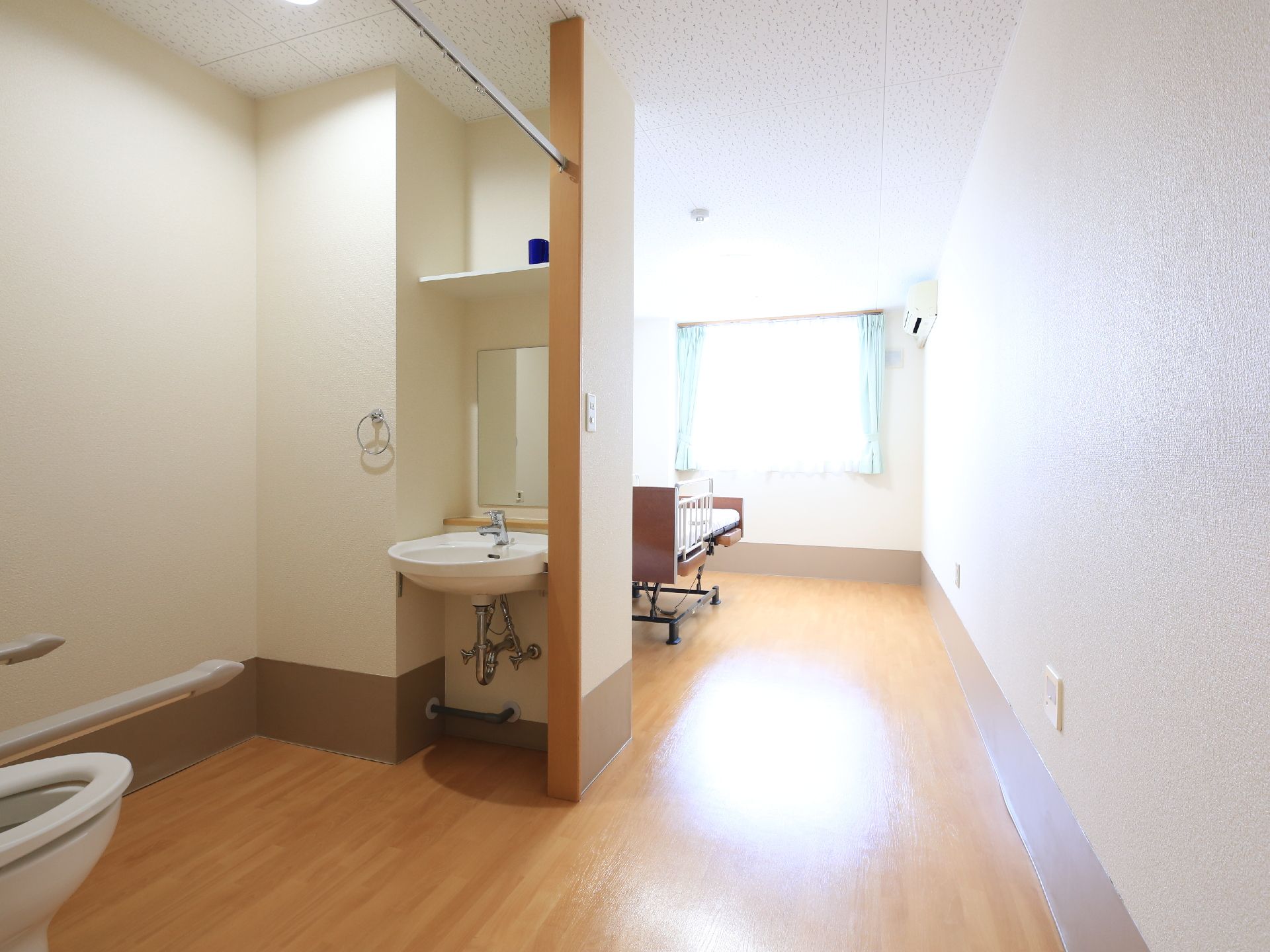 カーテンレールを備えたトイレの奥に、居住スペースがある間取りの居室