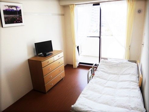ベッド、タンス、テレビなどが置いてある小さなワンルームタイプの部屋