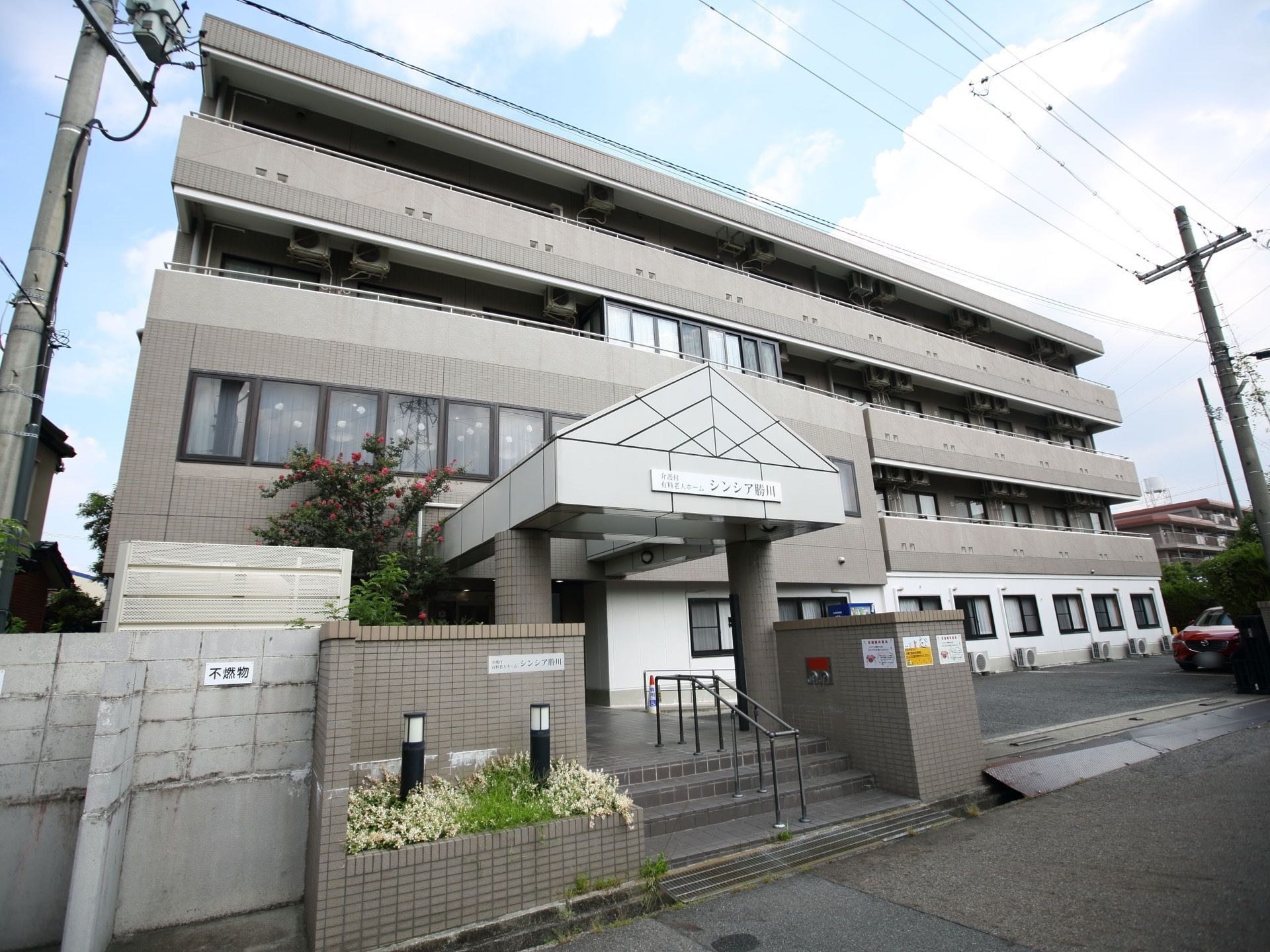 ４階建てのグレーの外装が落ち着いた雰囲気で、集合住宅のような外観。エントランスの通路は、階段とスロープが設置してある。
