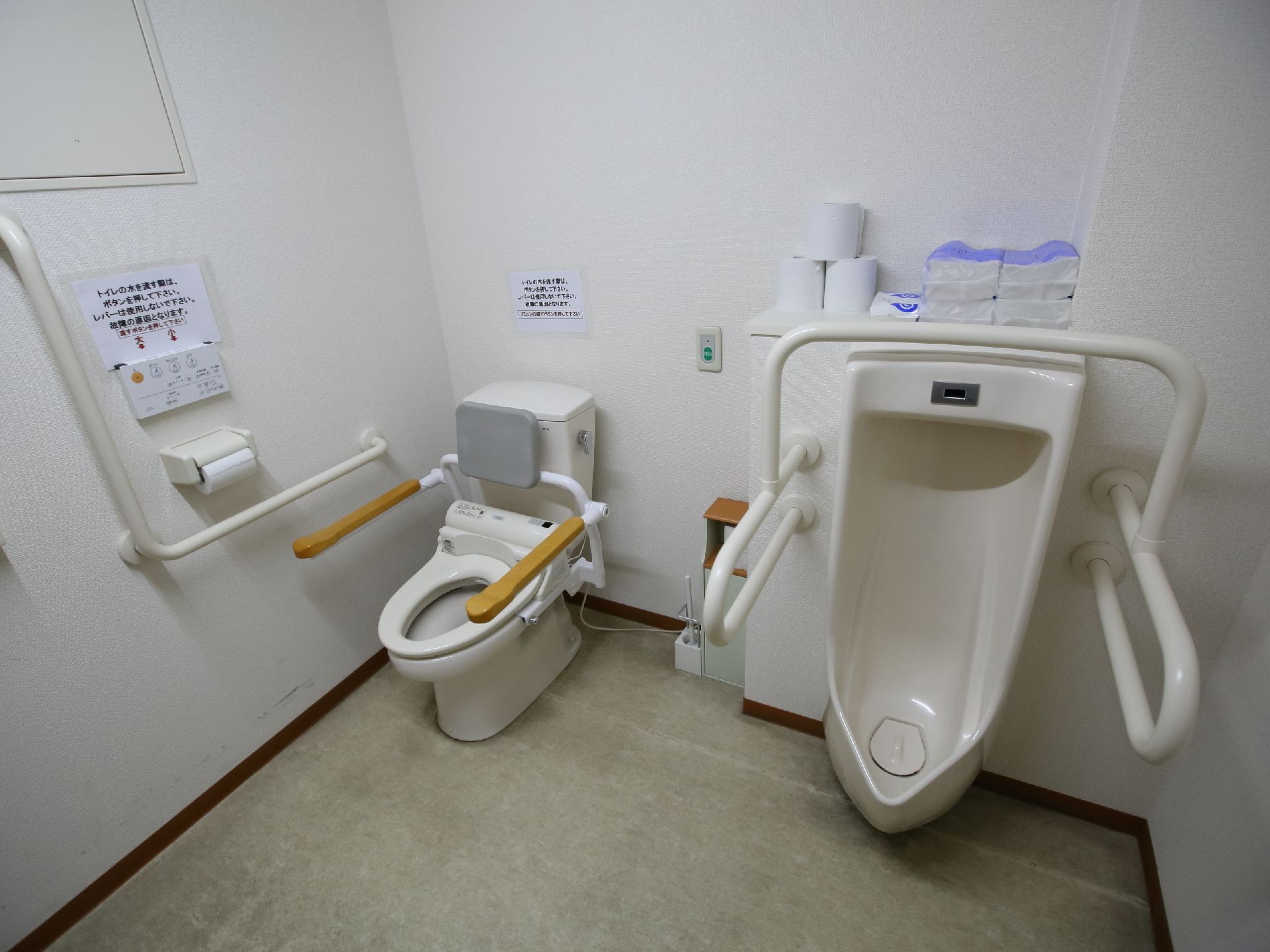 男性用小便器と大便座を併設し、いずれも手すりを備えたトイレ