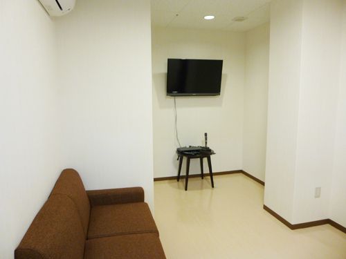 スッキリとしたシンプルな部屋である。エアコンやテレビモニター、カラオケが完備されている。壁際には、ソファが置かれている。