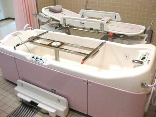 タイル張りの清潔な浴室には、専用ストレッチャーが備わった機械浴槽が完備されている。扉には、シャワーカーテンが採用されている。