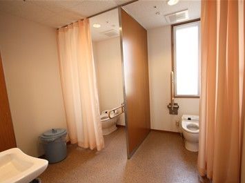 トイレの入り口は開閉を楽に行えるカーテンを使用しており、スタッフの駆けつけも迅速に行える。個室内は広々としている。