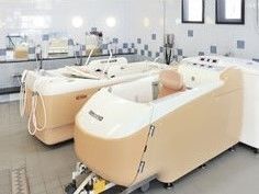 機械浴槽が２台設置された浴室のコーナー。白いタイルが貼られ、さわやかな印象。