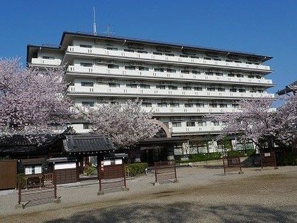 綺麗な花をつけた木々の向こうに見える、高層の施設外観