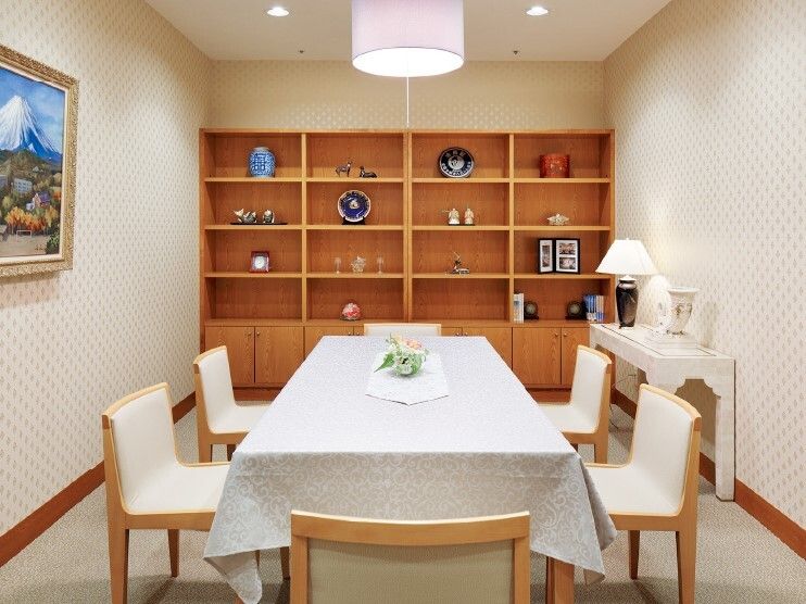 絵画が飾られた部屋には白いテーブルクロスがセットされたテーブルセットがあり、花が飾られている。