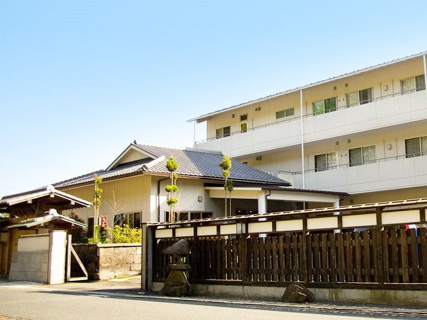日当たりのいい場所に建っている３階建ての建物は横に長く、各フロアにベランダが付き、和風の門もある。