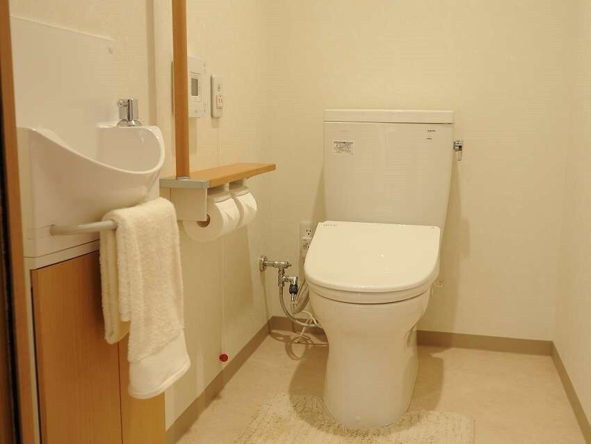 手すりと緊急コールがついた施設内のトイレの様子。広めのトイレの写真