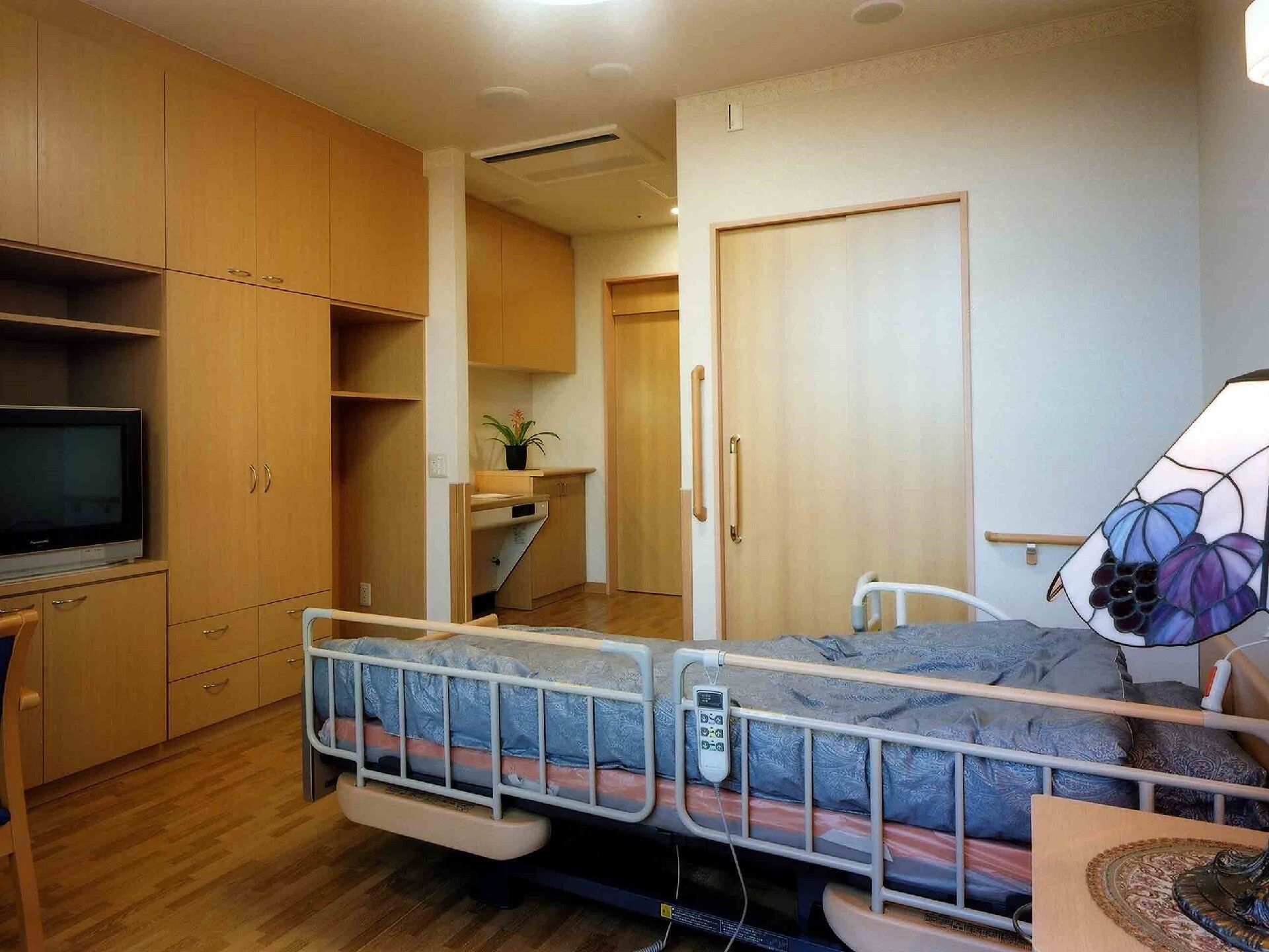 奥には畳が敷かれた本格的な和室があり、ちゃぶ台と座布団が置かれ、手前にはベッドやデスクセットが置かれている。