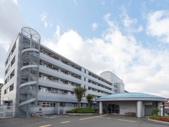 白を基調とした大きな建物の側面には屋外階段も付いている。駐車場もあり、各フロアにベランダが付いている。