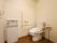 白い壁の部屋に置かれた手すりに囲まれたトイレと洗面台