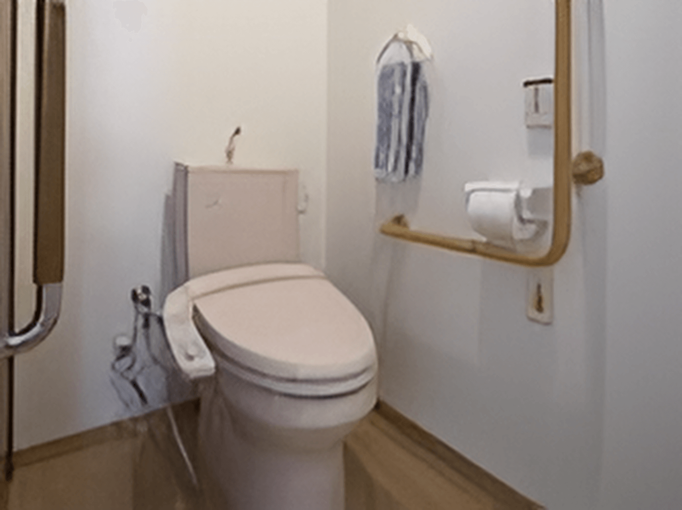 トイレの壁にはエル字型の手すりやトイレットペーパーホルダー、呼び出しボタンがある。