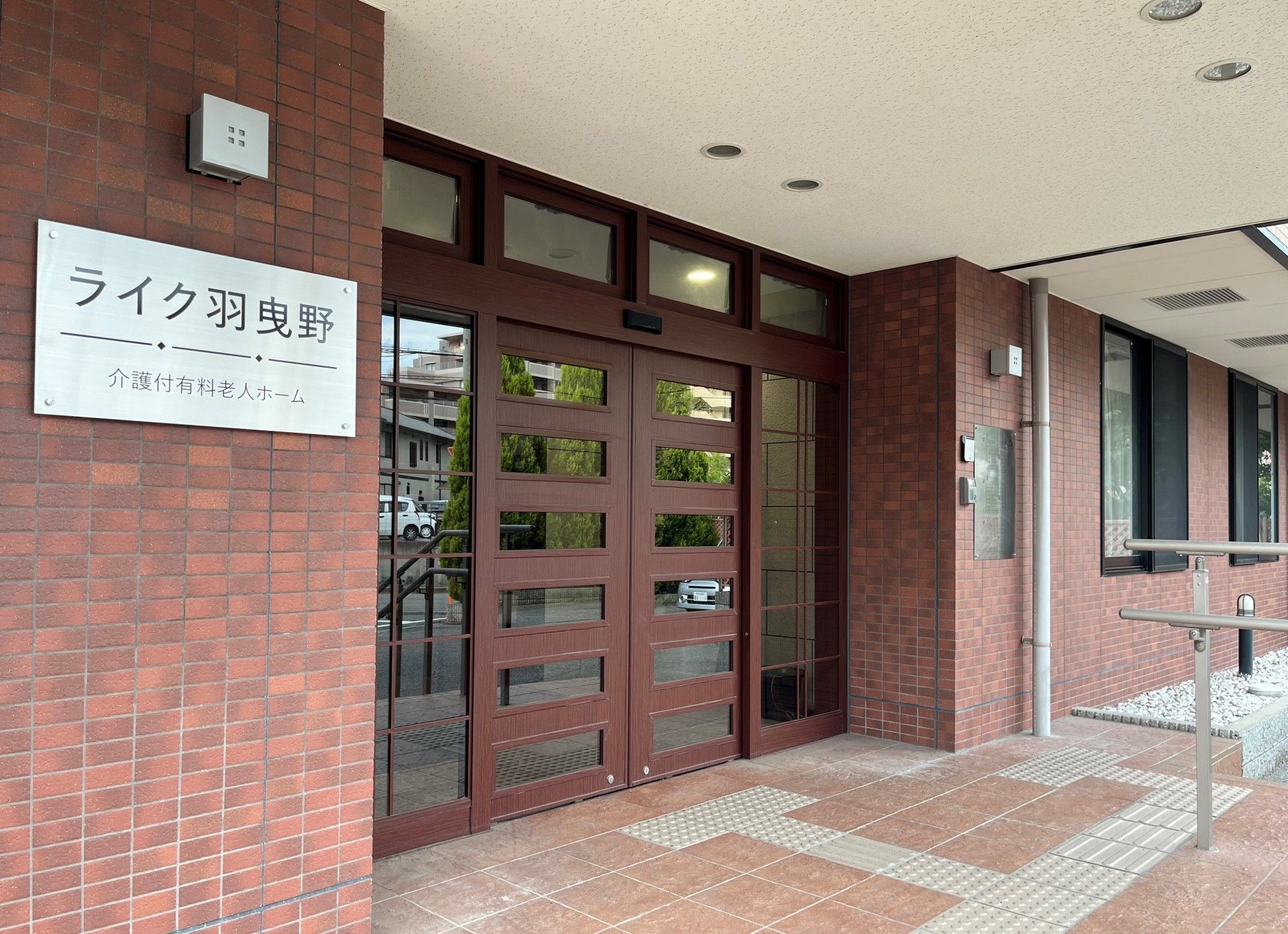 医療スタッフに車いすを押されて微笑んでいる。外に出て空気を感じている高齢者がひとり。リラックスしているので表情が柔らかい