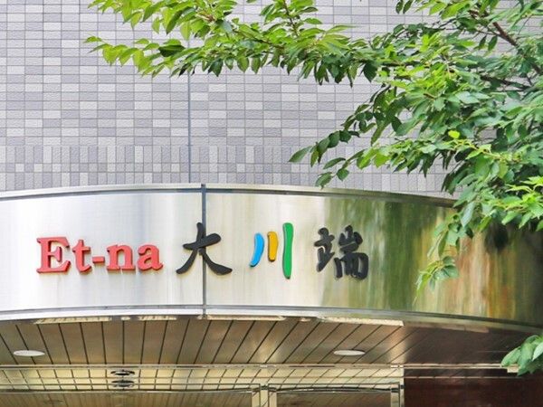 大きな木が植えられた玄関先にはホーム名が書かれている屋根が設置され、外壁はレンガ調。