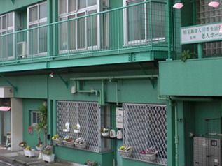 一階部分には建物に沿って花が咲いたプランターが並んでいる。窓にはラティスが取り付けてあり、そこにも花鉢が掛けてある。