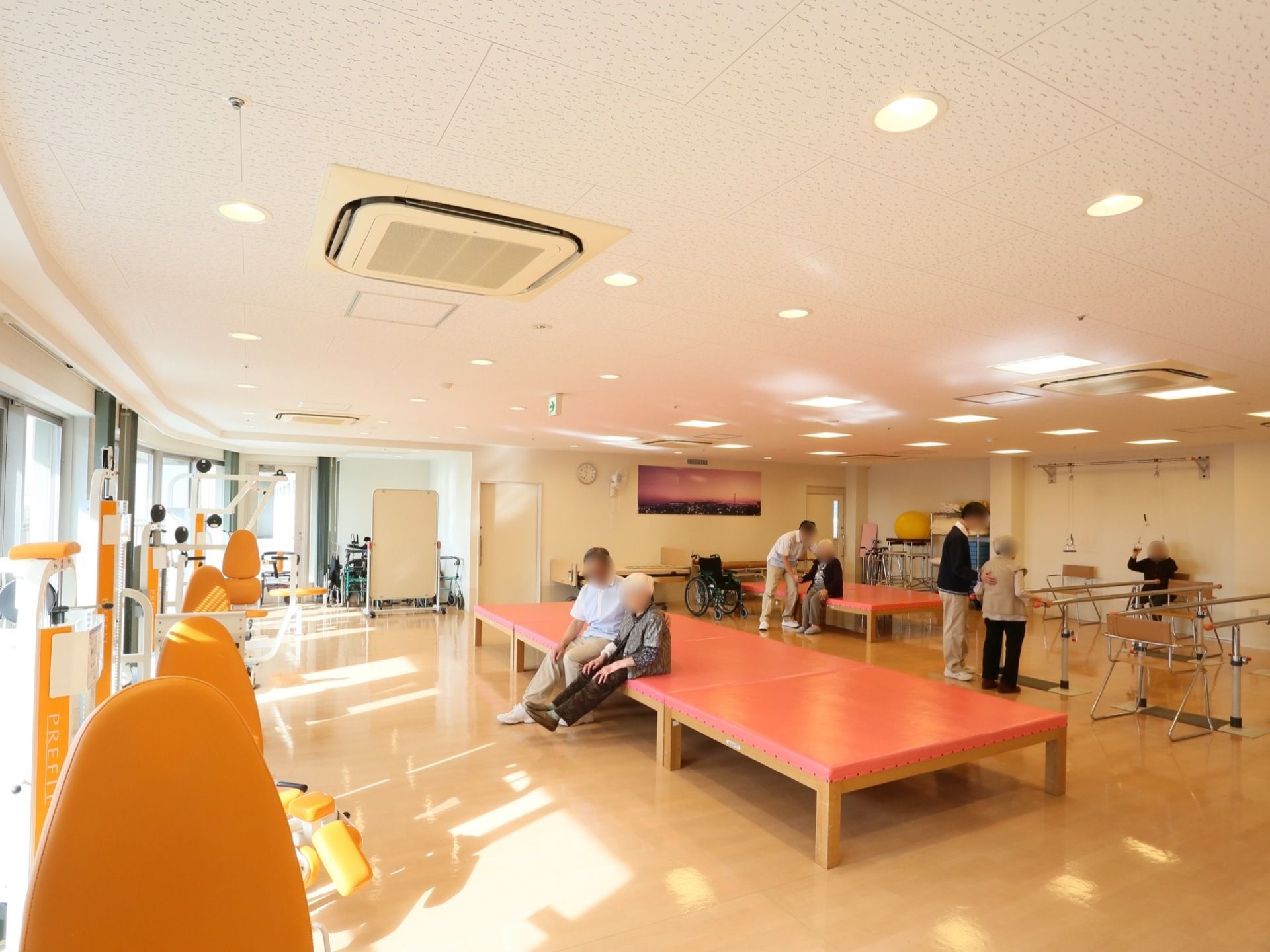 陽光のたくさん入る開放的な機能訓練室である。さまざまな機械を利用し、マンツーマンで丁寧な機能訓練が行われている。
