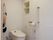 タンクレスの洋式トイレの横には、折りたたみ式の手すりが設置されている。壁にはＬ字の手すりと収納ニッチ、緊急コールが取りつけられている。
