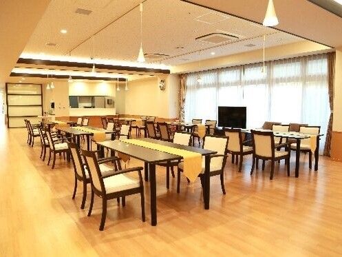 4人掛けのダイニングテーブルが並び、大きなテレビも設置された明るい雰囲気の食堂。
