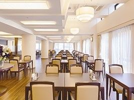 ベージュとブラウンでまとめられた食堂はレストランの雰囲気。窓にはレースのカーテンが設置され、明るい。