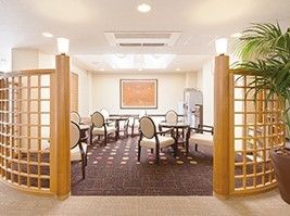 ソファやテーブルセットが置かれたラウンジ。大きな絵画が飾られ、木製のパーティションがある。
