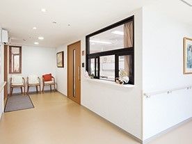 手すりが設置された白い壁には絵画も飾られ、廊下の突き当りには白と赤の椅子が3脚ならんでいる。
