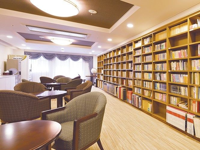 大きな木製の本棚が設置され、肘掛け椅子が丸いテーブルを囲んでいるセットが複数ある。