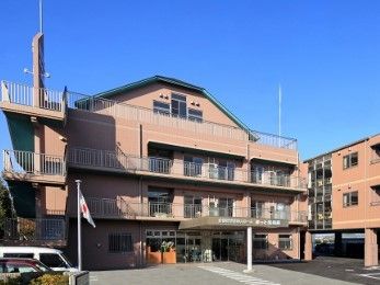 鉄骨造３階建ての建物の外観写真。駐車場スペースがある外側の敷地も写っている