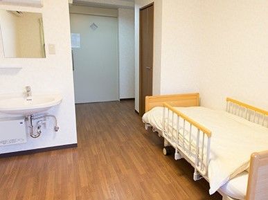 ベッドや洗面所があるフローリングの居室。洗面所は車いす対応の仕様。。