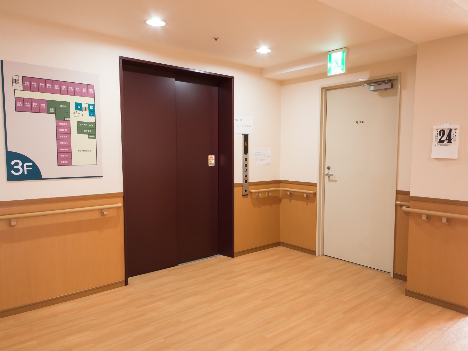 大きなエレベーターが１基設置されており、壁にはフロアマップが掲示されている。横には非常口が配置されている。