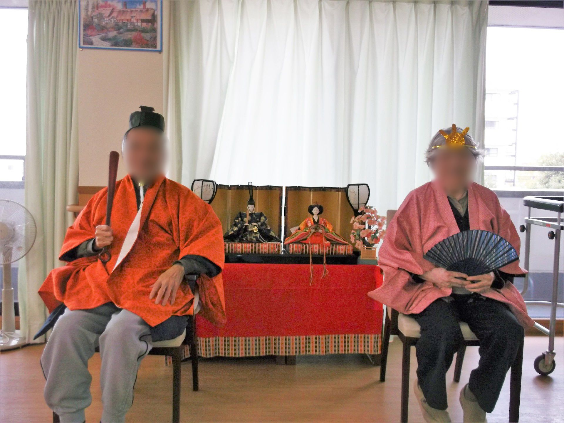 雛品業の両サイドの椅子にお内裏様とお雛様に扮した入居者が座っている。