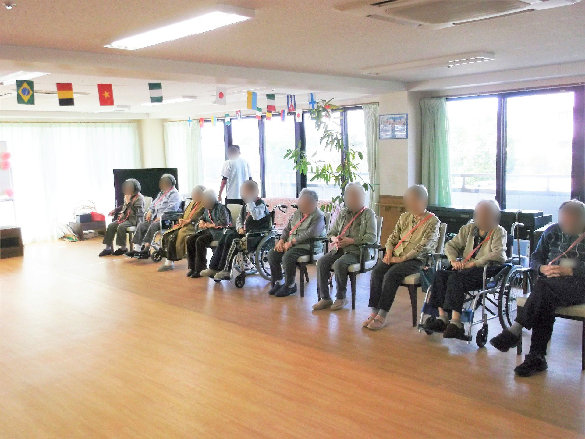 各国の国旗が飾られた館内。運動会には車いすの入居者も参加する。