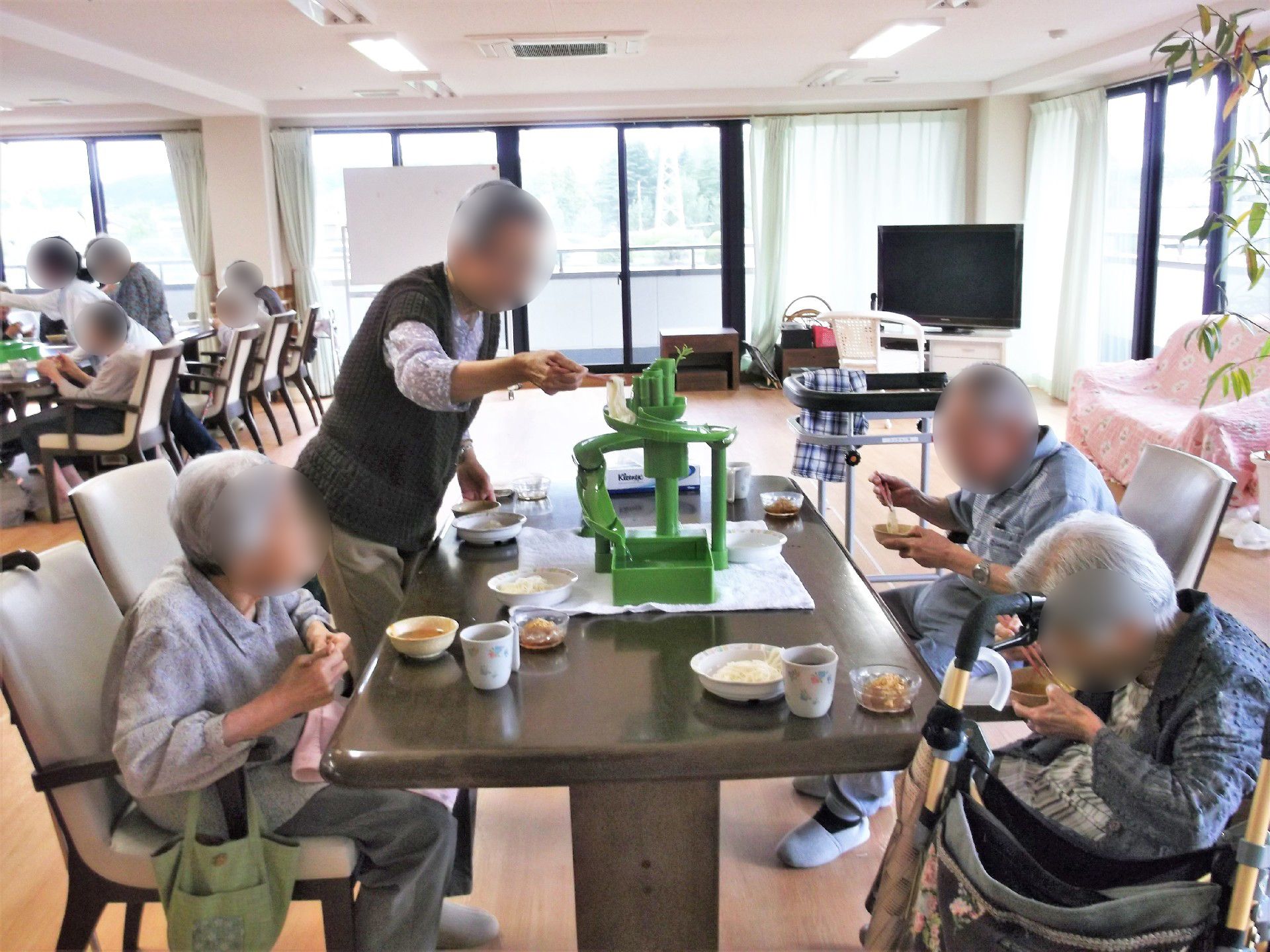 そうめん流しの機械を各テーブルに置き、上からそうめんを流して楽しむ入居者。