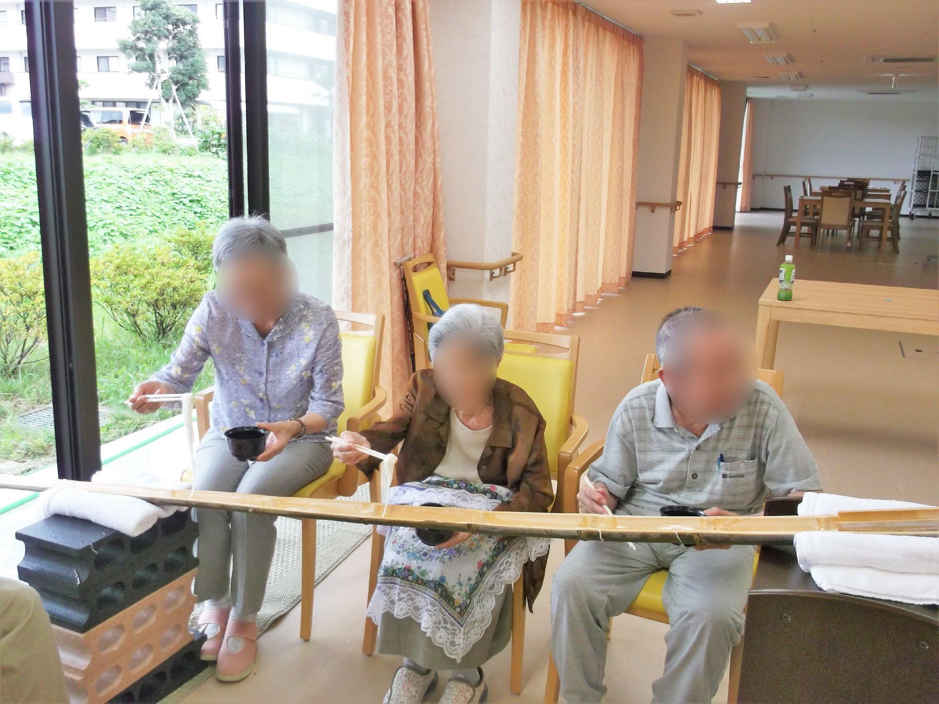 竹で作った本格的な流しそうめんを楽しむ入居者の様子。