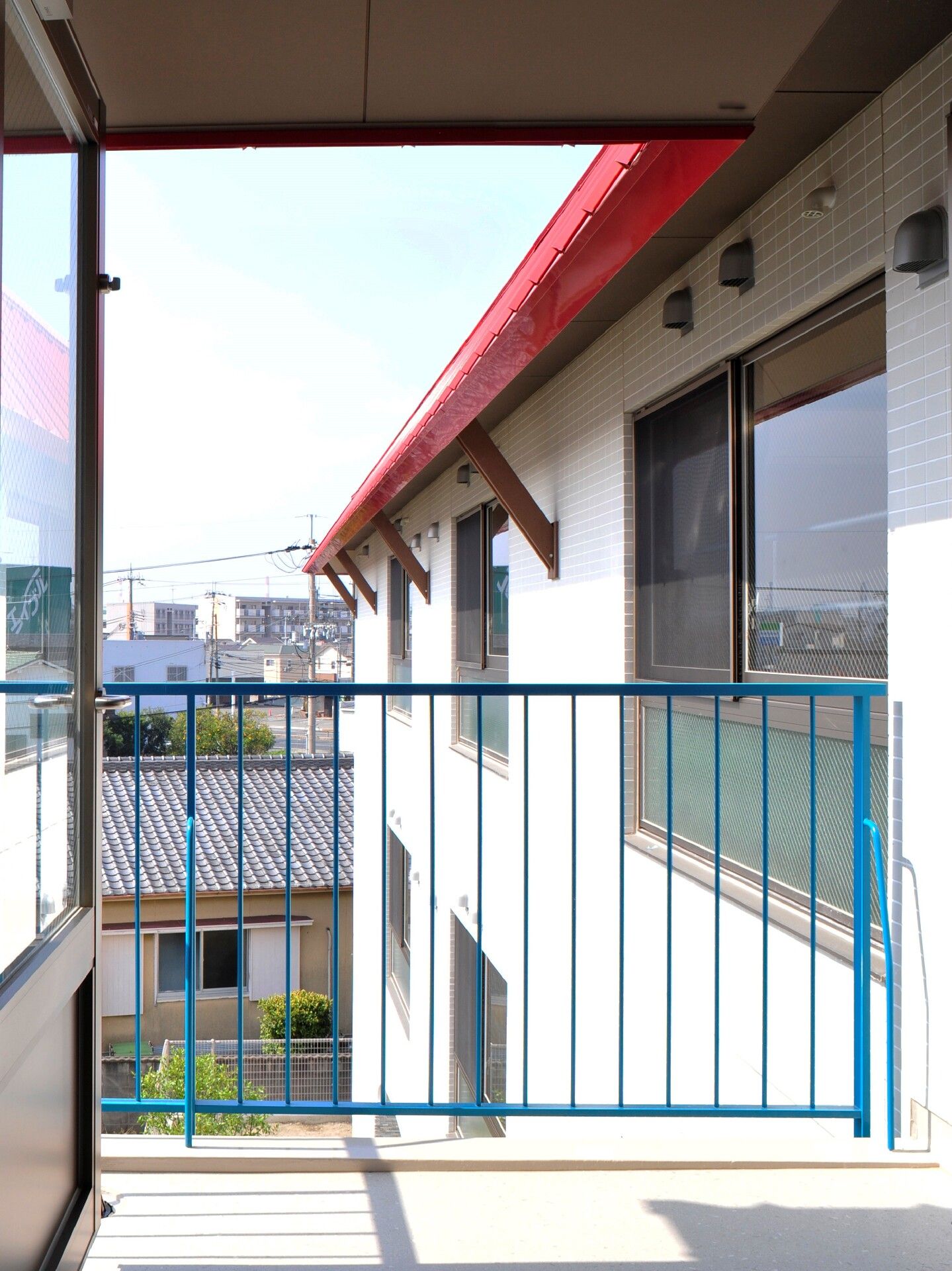 周辺の住宅地を見渡すことができるバルコニーには青い手すりが付き、日当たりもよい。
